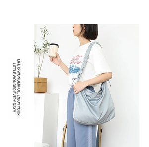 Close-up of light blue nylon hobo bag with unique pleated shoulder strap and drawstring