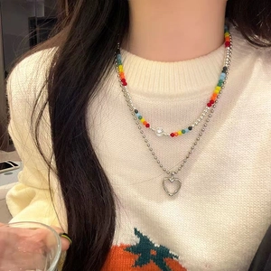 Rainbow crystal beaded necklace with hollow heart pendant shown on model's sweater