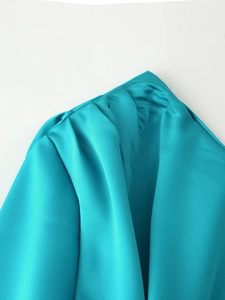Detail of teal satin fabric featuring elegant pleated shoulder design and glossy finish