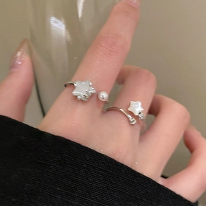 Detail view of silver star and pearl adjustable ring worn on a finger