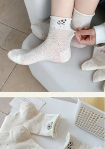 Close-up of cotton crew socks with colorful speckles and cute animal embroidery