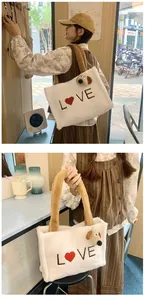 Detail of white plush tote bag featuring LOVE embroidery and a cute puppy charm