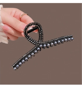Detail of a large black metal shark hair clip with grey pearls and black rhinestones