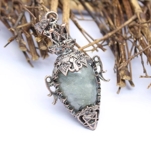 Macro shot of vintage copper bottle pendant with grey-green gemstone and star detail
