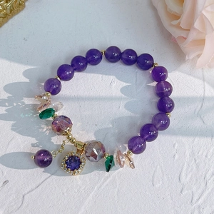 Detail of amethyst bracelet with flower charm, zircon inlay, and golden metal accents
