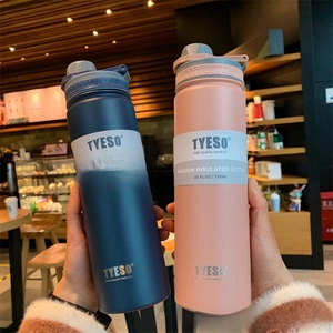 Close-up of TYESO 750ml thermal bottles with carry handles in a warm cafe setting
