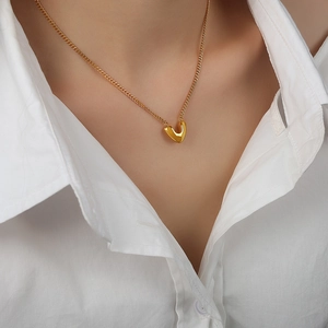 Collier en V doré en acier titane sur un mannequin portant une chemise blanche