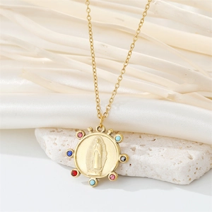 Close-up of golden Virgin Mary pendant with colorful rhinestones on a white rock base