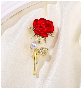 Macro view of a red rose brooch with gold details, sparkling crystals and a white pearl