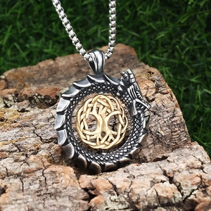 Detailed dragon Ouroboros pendant with Tree of Life symbol on natural wood and grass