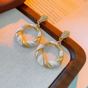 Detail view of vintage enamel twisted hoop earrings on a textured linen display tray
