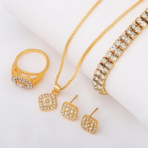 Detail of gold luxury jewelry set with square zircon pendants and tennis bracelet
