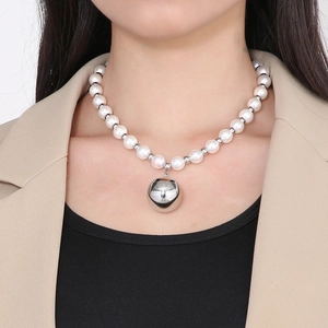 Close-up of elegant pearl necklace with a large hollow silver steel bead pendant