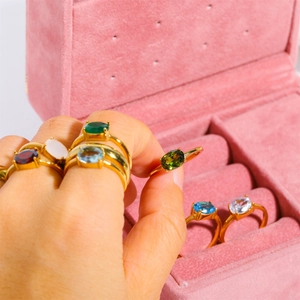 Golden stainless steel birthstone rings with colorful zircon crystals in pink jewelry box