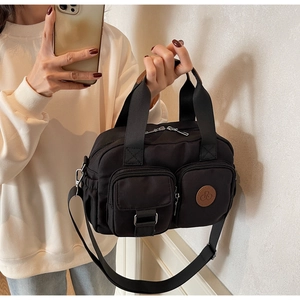Details einer schwarzen Nylon-Schultertasche mit Lederakzenten und Taschen-Design