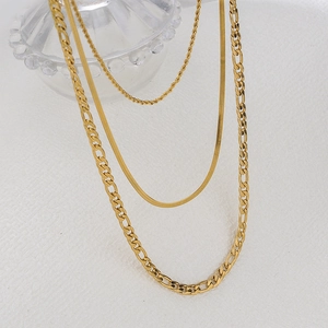 Close-up of gold layered chain set featuring rope, snake, and figaro necklace details