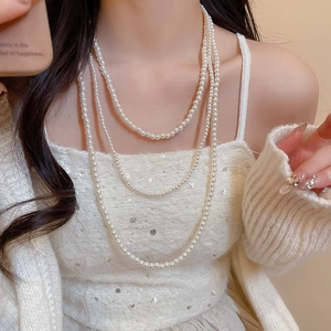 Dettaglio ravvicinato di una collana di perle elegante a tre strati su una modella per un look vintage