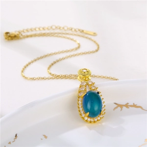 Detailed view of teardrop color-changing pendant with blue stone and gold chain