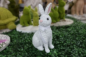 Detail of white resin rabbit with woven texture and a ribbon bow for garden decor