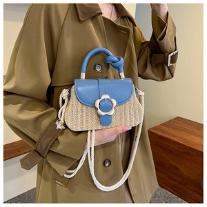 Détail du rabat en cuir bleu et du corps en paille tressée avec fermoir en fleur dorée