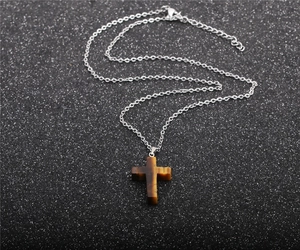 Macro detail of natural tiger eye cross pendant with polished stainless steel chain