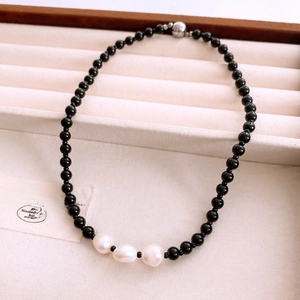 Detail of beaded necklace with black beads and baroque pearls in a velvet jewelry box
