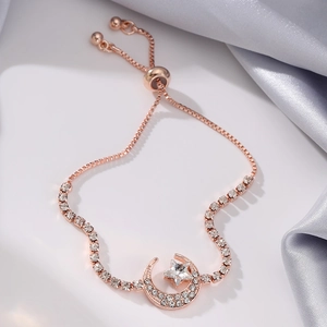 Detail of rose gold celestial bracelet featuring crystal moon and star charm on satin