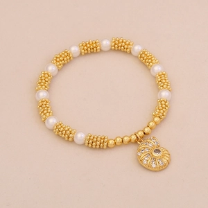 Close-up of pearl and gold beaded bracelet featuring a sparkling rhinestone conch charm
