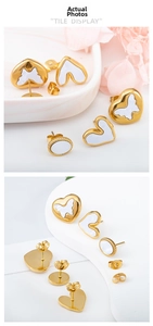 Detailed tile display of gold stainless steel shell stud earrings with white heart motifs