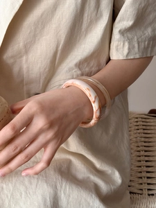 Detail shot of marble white and amber resin bangles styled on a model wrist