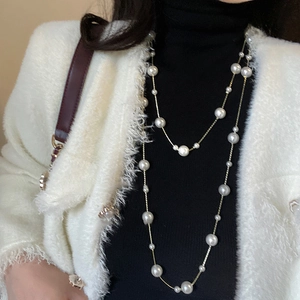 Elegant double-layer long pearl necklace with gold chain on a black turtleneck sweater