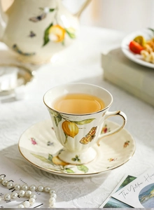 Detail of ceramic tea cup and saucer set with lemon butterfly pattern and gold rim edge