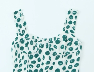 Detailed close-up of white dress fabric with green polka dot print and heart neckline