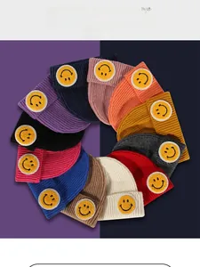 Flat lay of colorful ribbed knit beanies in eleven vibrant shades with smiley patches