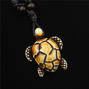 Detail of resin sea turtle pendant with bone-like texture and black woven cord