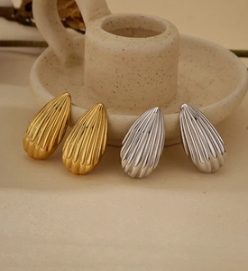 Detailed view of teardrop earrings with vertical stripes in gold and silver finishes