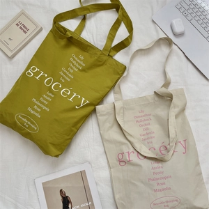 Détail du sac cabas en toile avec texte floral sur un tissu blanc texturé