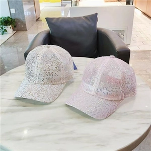 Detail showing white and light pink sequin baseball caps with sparkling finish