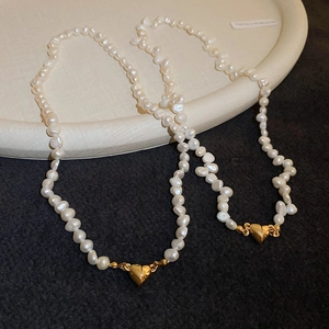 Macro view of 18K gold heart magnetic clasps on a baroque freshwater pearl necklace