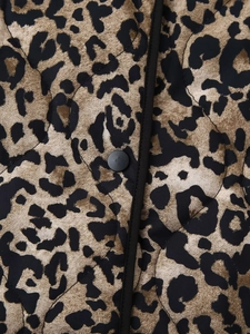 Macro view of leopard print quilted jacket featuring black piping and functional snap button