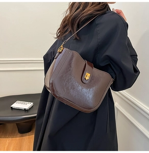 Detail of dark brown leather saddle bag with glossy finish and gold metal buckle