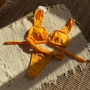 Detailed flat lay of vibrant yellow bikini featuring decorative starfish metal buckle