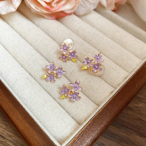 Detail of purple enamel flower earrings and clip-ons displayed in a velvet jewelry box