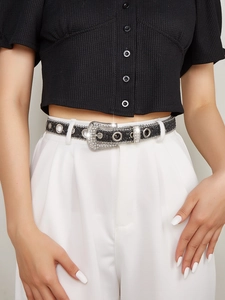 Detail of a thin black glitter belt with a rhinestone buckle on white trousers