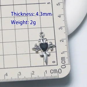 Gothic silver alloy cross pendant with black heart gemstone on measuring grid