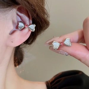 Macro shot of bow-shaped ear cuff with heart-shaped white opal and pink crystal