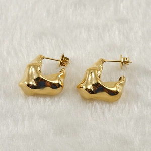 Gold-plated irregular geometric stainless steel earrings on a soft white plush surface