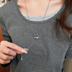 Close-up of adjustable silver pony pendant necklace on a grey sweater