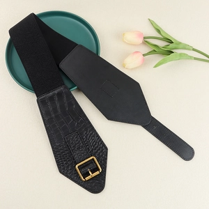Close-up of black crocodile-embossed wide belt with golden buckle on elegant setting
