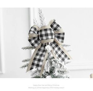 Close-up of black and white buffalo plaid bow with burlap trim on a snowy Christmas tree